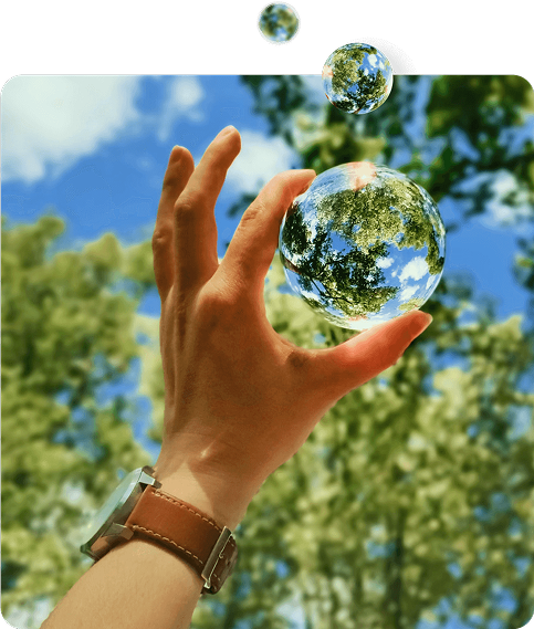 Mano elevándose hacia una burbuja que refleja árboles y cielo, simbolizando cuidado del entorno natural