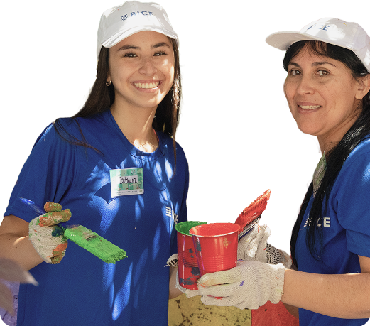 Dos voluntarias de BICE pintando en una actividad comunitaria, sonriendo y usando implementos de trabajo