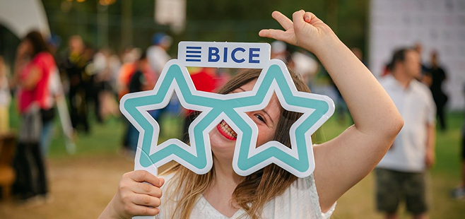 Mujer sonriendo mientras sostiene un marco con estrellas y el logo BICE durante una actividad corporativa