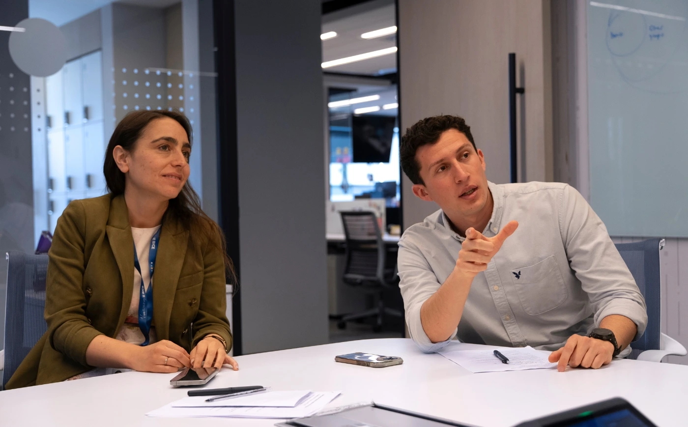 Dos colaboradores de BICE en una reunión de trabajo, conversando y revisando documentos en una sala corporativa