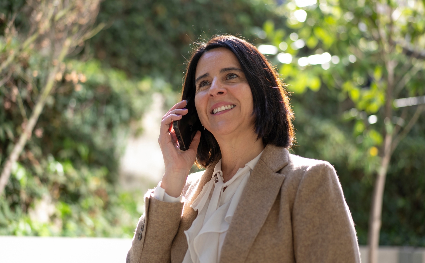 Ejecutiva de BICECORP sonriendo mientras habla por teléfono al aire libre