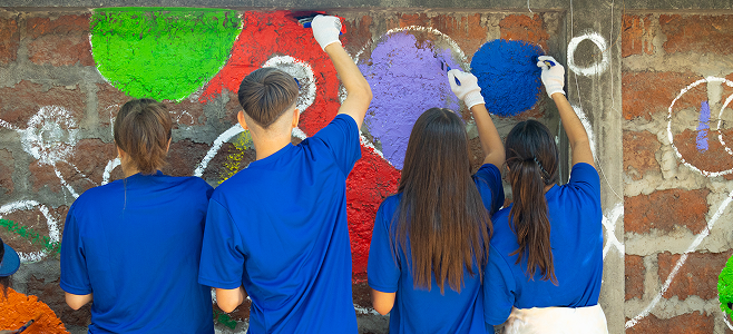 Grupo de voluntarios pintando un mural comunitario con colores vivos durante una actividad de BICE