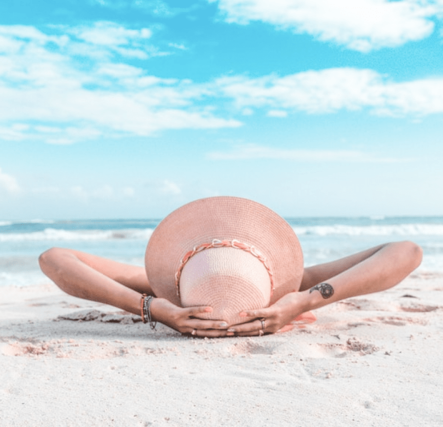 Una mujer recostada en la playa frente al mar.