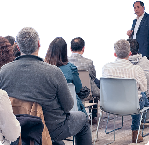 Colaboradores asistiendo a una charla corporativa mientras un expositor presenta al frente de la sala